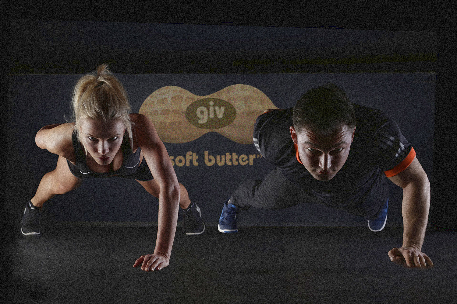 A man and woman doing one handed push ups fueling with giv soft butter organic peanut butter for pre workout energy and post workout recovery nutrition.